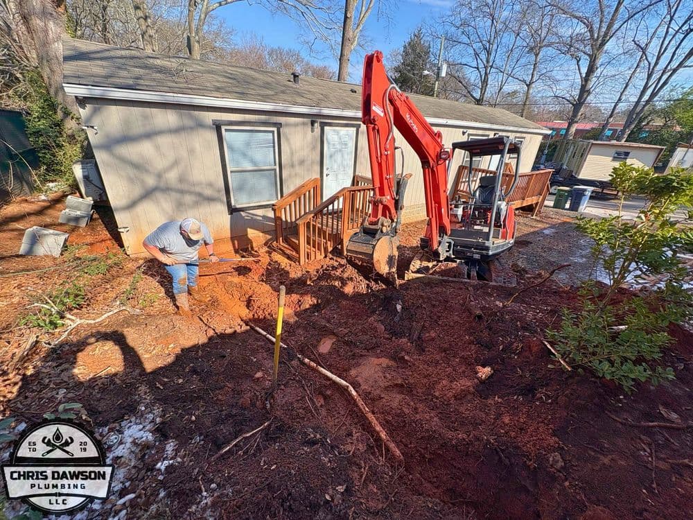 Plumber using excavator for home foundation repair in residential yard.