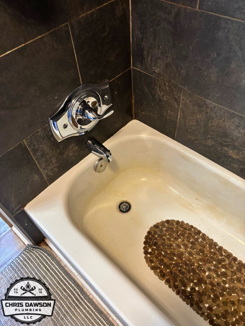 Bathroom tub with modern faucet and pebble mat, showcasing plumbing work by Chris Dawson Plumbing.