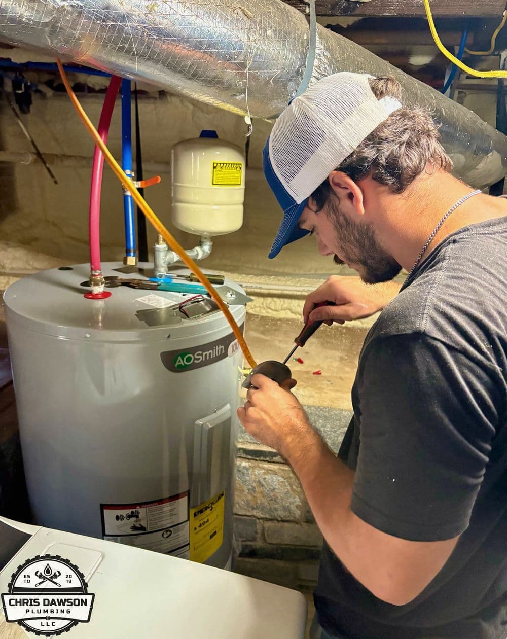 Plumber servicing AO Smith water heater in a basement, ensuring optimal performance.